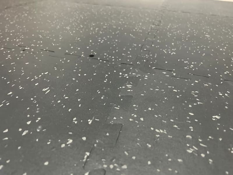 Um carro estacionado sobre um rolo de borracha preta, com um grande plano do pneu.